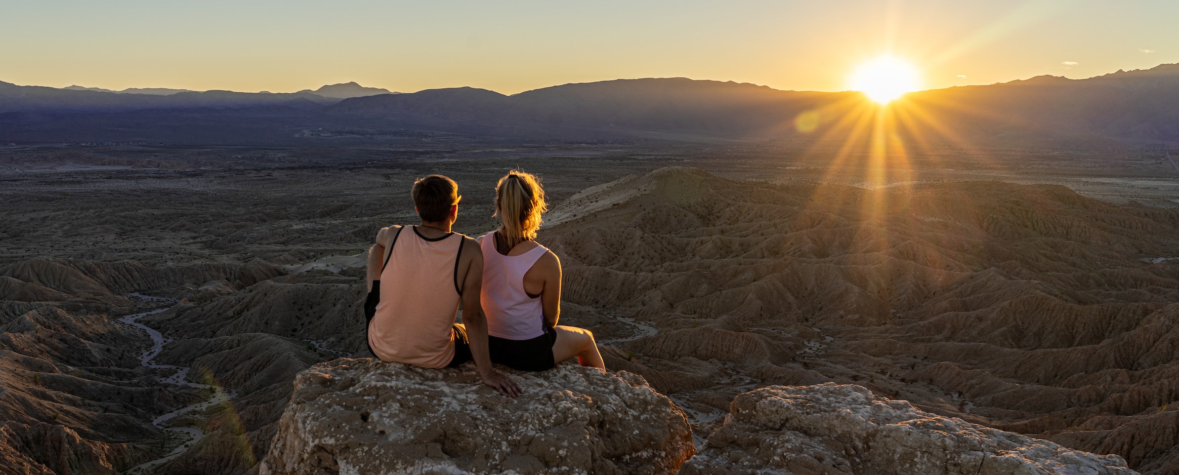 Couple seated on rocks facing the sunset over the desert at Anza Borrego State Park